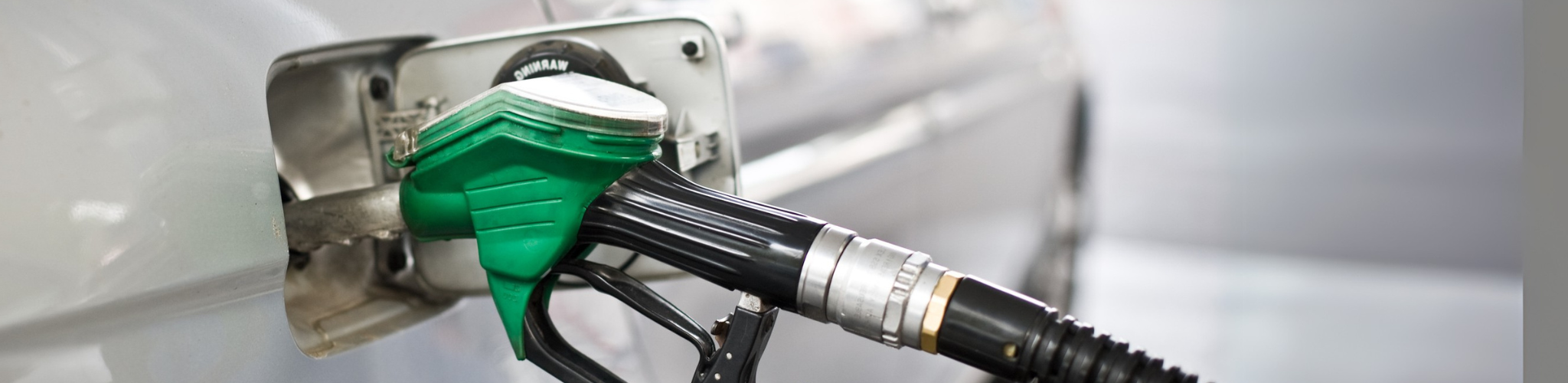 green fuel pump head inserted into the gas tank of a a white car